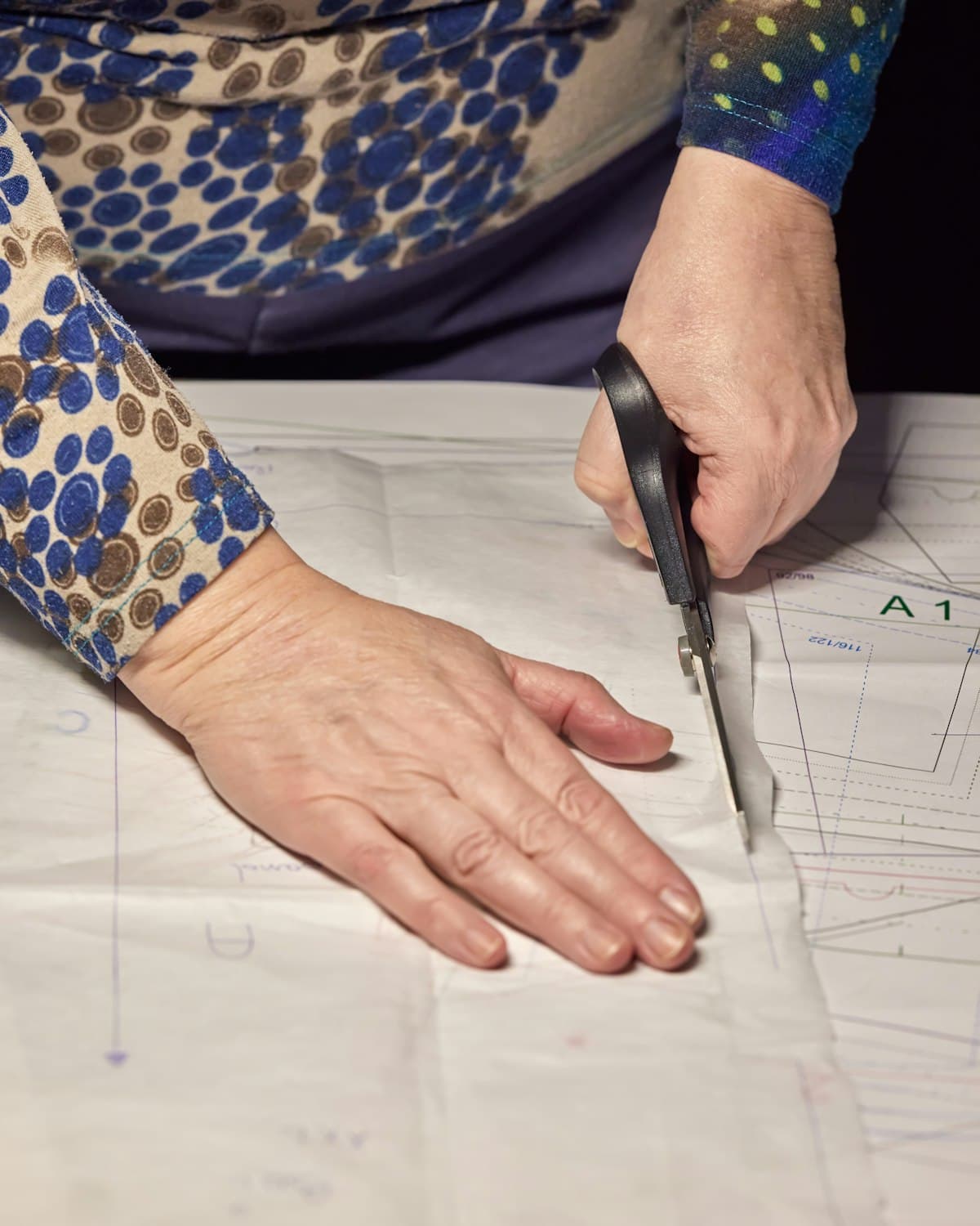 Hands cutting a paper sewing pattern